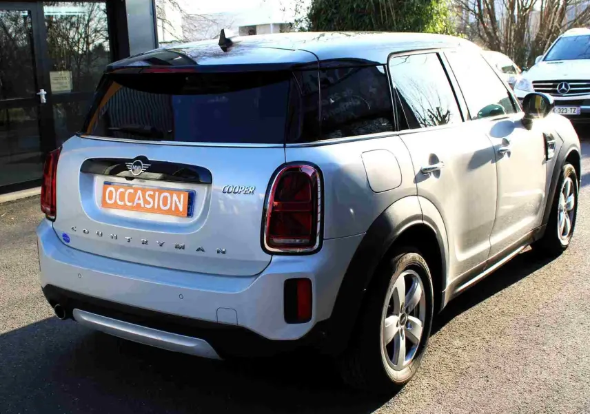 Vue 3/4 arrière droite d'une MINI Countryman gris perle métal avec toit noir et feux arrière foncés, en extérieur.