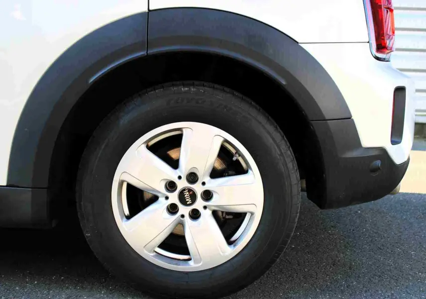 Gros plan sur la roue arrière droite d'une MINI Countryman gris perle avec jante argentée et entourage noir.