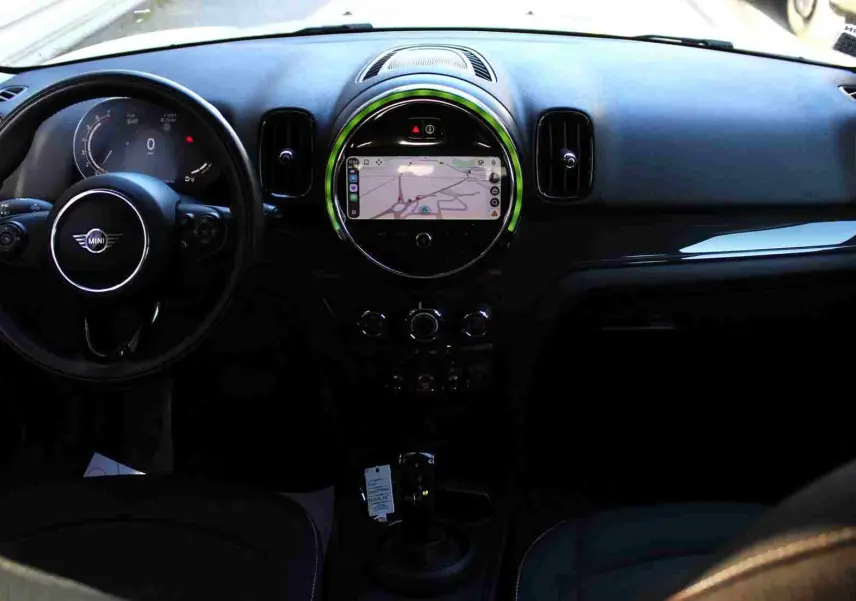 Tableau de bord et volant noir de MINI Countryman II avec écran central circulaire affichant la navigation GPS.