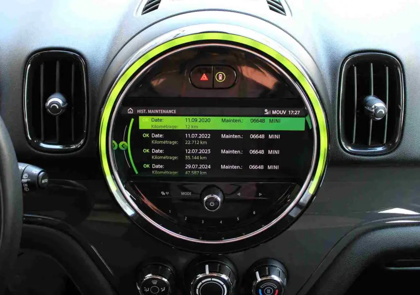 Vue rapprochée du tableau de bord noir du MINI Countryman 2020 avec écran central rond affichant l'historique de maintenance.