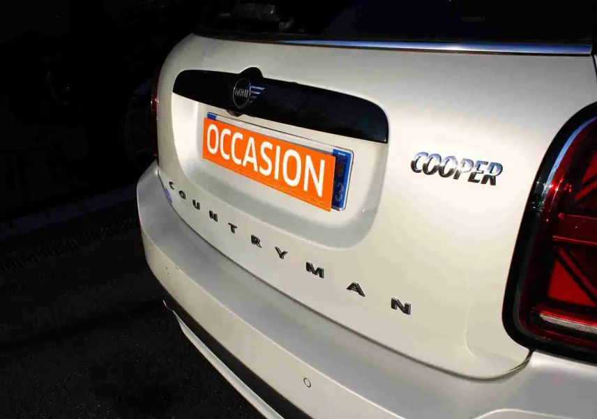 Vue arrière droite d'une MINI Countryman gris perle métal avec toit noir et badge Cooper visible.