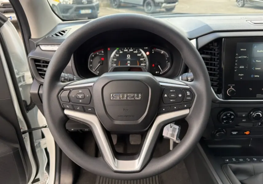 Vue intérieure centrée sur le volant multifonctions noir d'un Isuzu D-MAX 2026 avec tableau de bord et écran tactile.