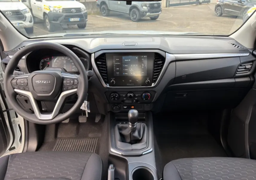 Vue intérieure avant de l'Isuzu D-MAX 2.2 TD 164 Space Evolution avec tableau de bord noir et volant multifonctions.