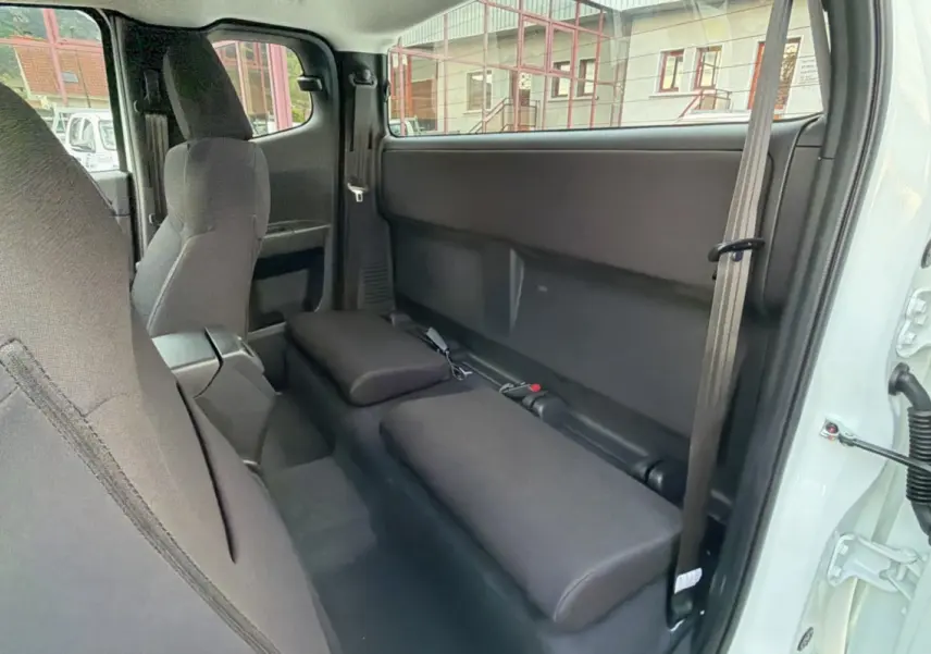 Vue intérieure côté droit du pick-up Isuzu D-MAX Splash White 2026, montrant les sièges arrière rabattus en tissu noir.