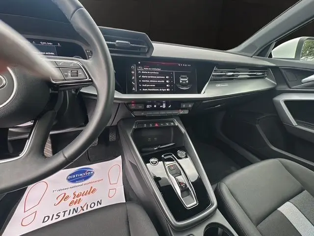 Vue intérieure de l'Audi A3 Sportback 2024, tableau de bord et console centrale noirs avec écran digital large.