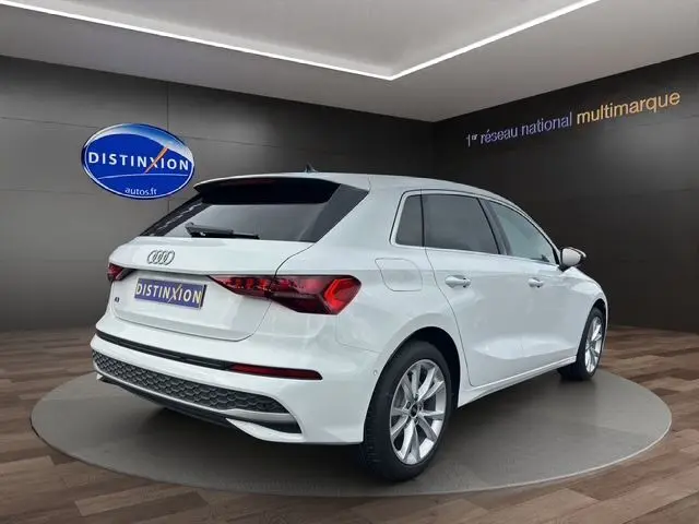 Audi A3 Sportback blanc Arkona vue 3/4 arrière droit en intérieur avec jantes alliage léger et feux LED distinctifs.
