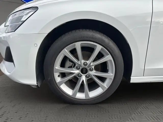 Gros plan sur la roue avant gauche d'une Audi A3 Sportback blanche Arkona avec jante alliage léger à 5 branches doubles.