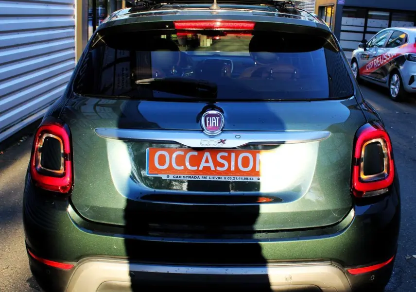 Vue arrière d'un FIAT 500X vert Toscane métallisé avec feux arrière LED et attelage visible en stationnement.