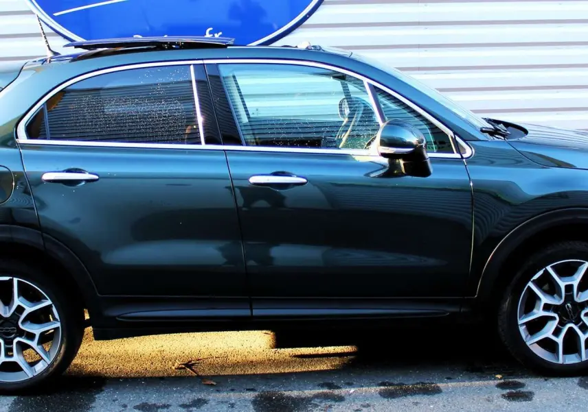 Profil côté gauche d'un FIAT 500X vert Toscane métal 2019, avec jantes alliage et poignées chromées visibles.