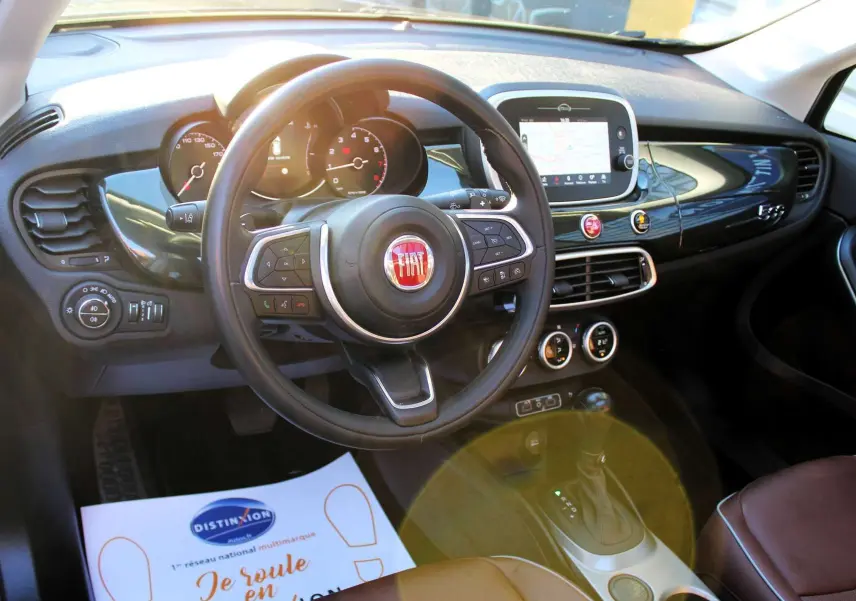 Intérieur de la Fiat 500X 2019 vu de face, tableau de bord noir brillant avec volant multifonction et écran tactile central.
