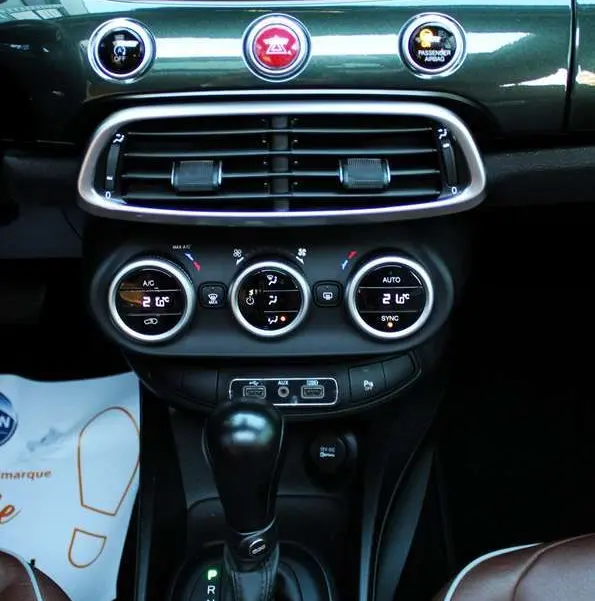 Vue rapprochée du tableau de bord vert Toscane métallisé de la Fiat 500X avec levier de boîte auto et sellerie marron.