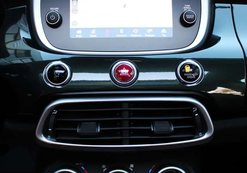 Tableau de bord de la Fiat 500X vert Toscane, avec écran tactile central et commandes de climatisation visibles.