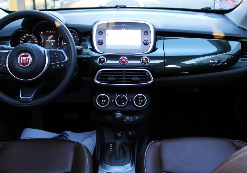 Intérieur du Fiat 500X 2019 avec tableau de bord vert Toscane métal, volant multifonction et sièges cuir marron.