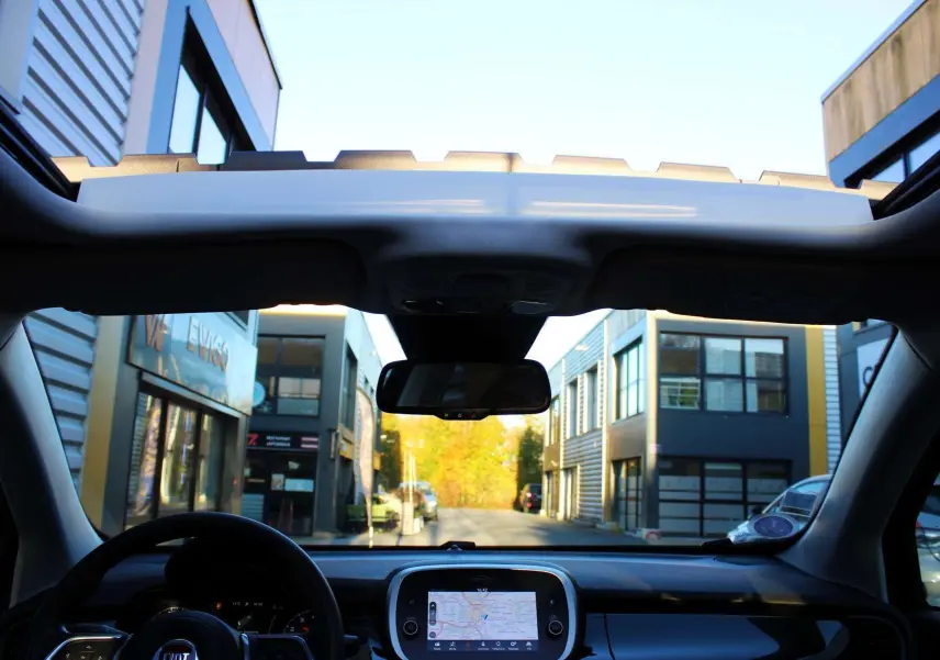Vue intérieure du tableau de bord et toit ouvrant du Fiat 500X 2019 avec écran tactile de navigation allumé.