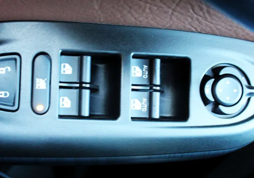 Gros plan sur les commandes de lève-vitres et réglage des rétroviseurs côté conducteur d'une FIAT 500X 2019.