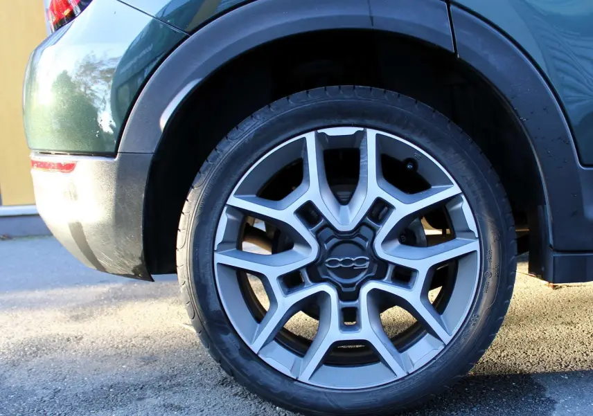 Gros plan sur la roue arrière droite d'une FIAT 500X vert Toscane métal avec jante alliage au design étoilé.