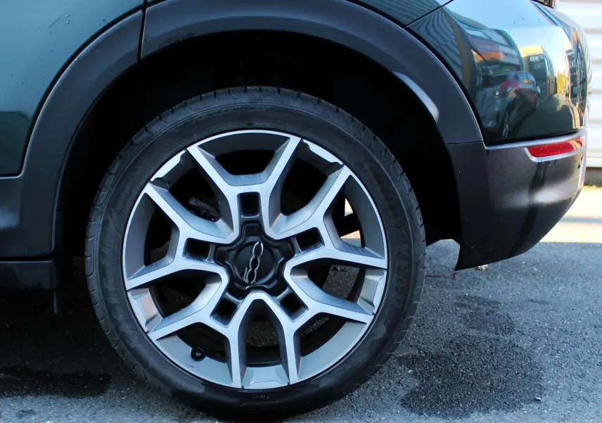Gros plan sur la roue arrière droite d'une FIAT 500X vert Toscane métal, avec jante alliage bicolore et logo central 500.