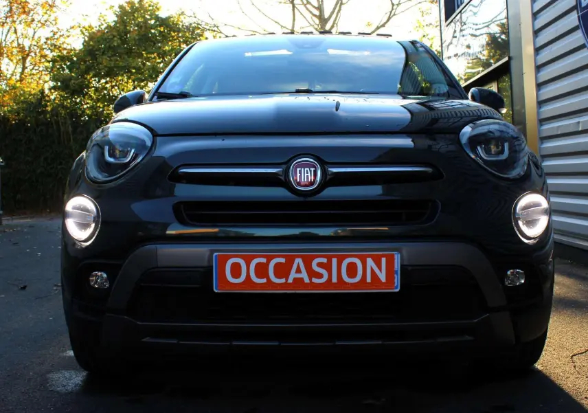 Vue frontale d'un FIAT 500X vert Toscane métal avec phares allumés et plaque "OCCASION" visible.