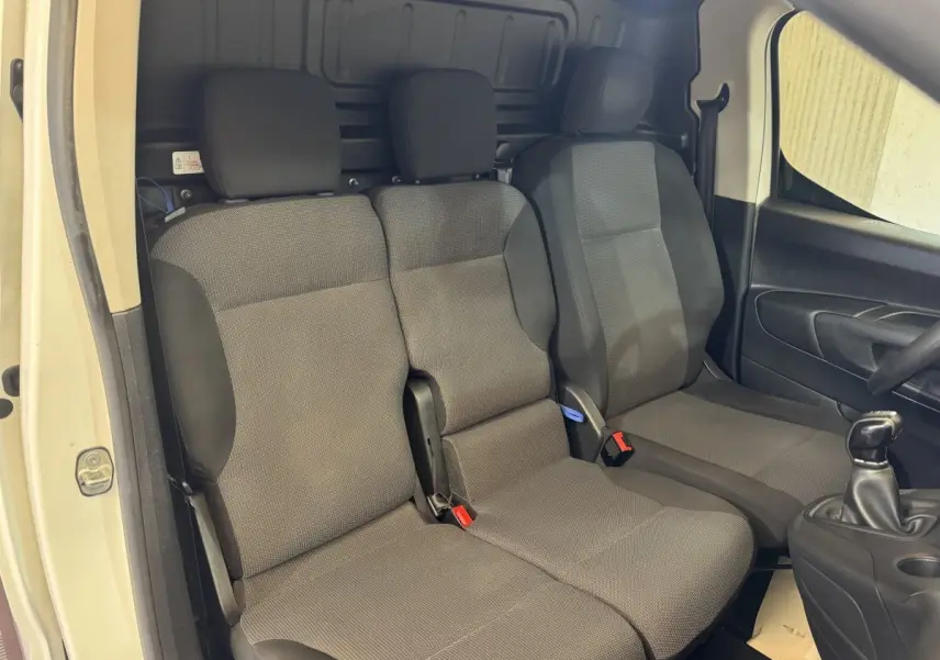 Vue intérieure côté conducteur du Citroën Berlingo blanc 2020, montrant les sièges avant en tissu gris et la boîte manuelle.