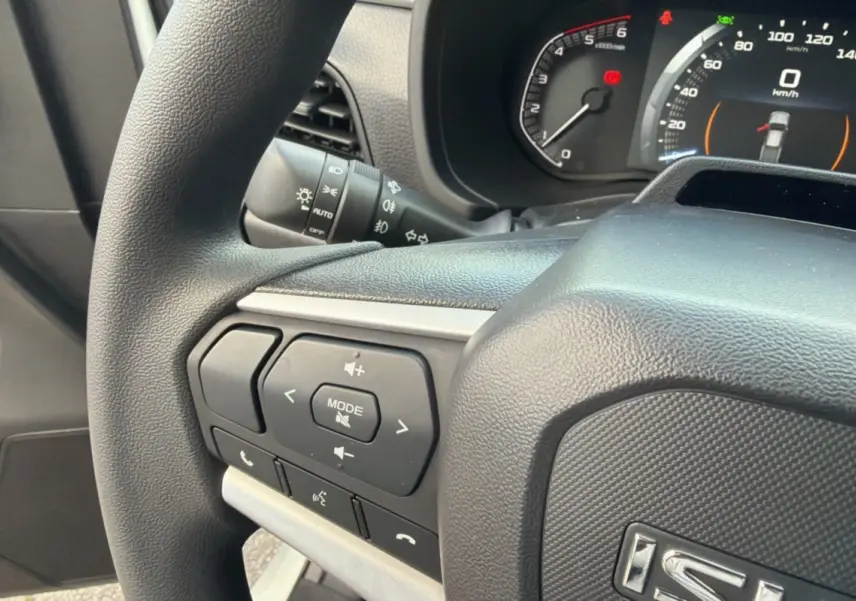 Gros plan sur le volant multifonctions noir de l'Isuzu D-MAX 2026 avec commandes audio et tableau de bord numérique.