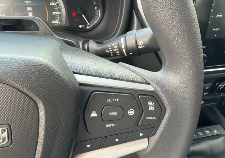 Gros plan sur le volant multifonctions noir de l'Isuzu D-MAX 2.2 TD 164 Space Evolution avec commandes de régulateur de vitesse.