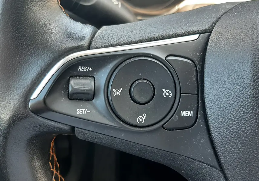 Gros plan sur les commandes de régulateur de vitesse au volant en cuir noir de l'Opel Crossland noir toit blanc 2019.