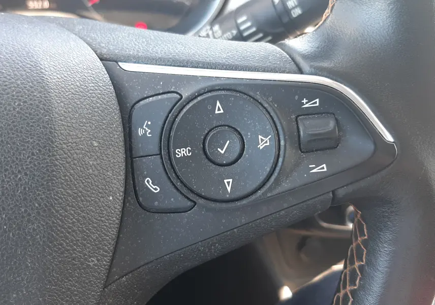 Gros plan sur les commandes du volant côté gauche de l'Opel Crossland noir avec toit blanc, montrant les boutons multifonctions.