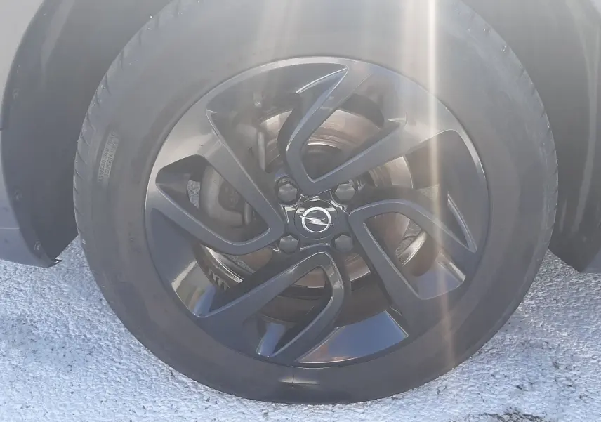 Gros plan sur la roue avant gauche de l'Opel Crossland noir avec jante noire au design moderne et logo Opel central.