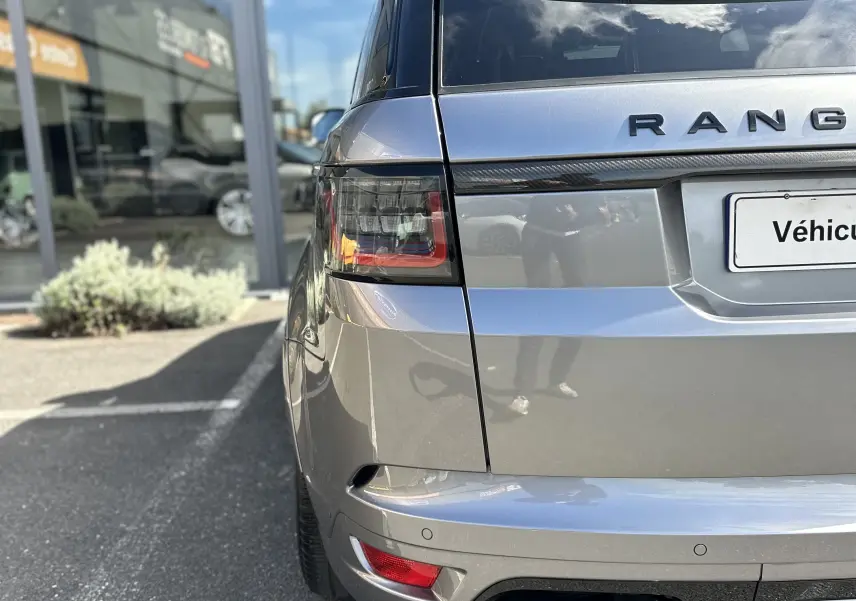 Vue arrière côté gauche d'un Range Rover Sport gris foncé 2020 avec double sortie d'échappement et feux arrière LED.