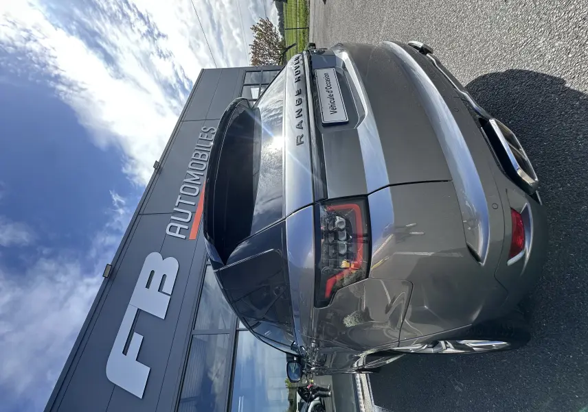 Vue 3/4 arrière droite d'un Range Rover Sport gris foncé 2020 devant un bâtiment FB Automobiles.