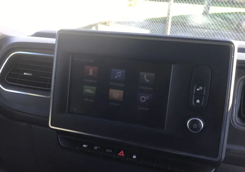 Vue intérieure de la partie arrière ouverte d'un Renault Master blanc 2020 avec étagères métalliques et parois boisées.