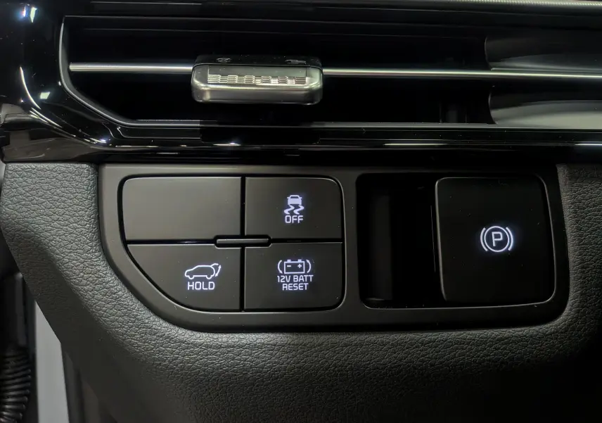 Boutons de commande du frein à main électrique et fonctions d'assistance sur le tableau de bord du KIA SPORTAGE gris céramique 2025.