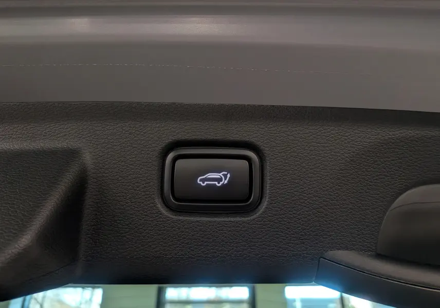 Bouton d'ouverture électrique du hayon sur le coffre intérieur d'un KIA SPORTAGE gris céramique toit noir.