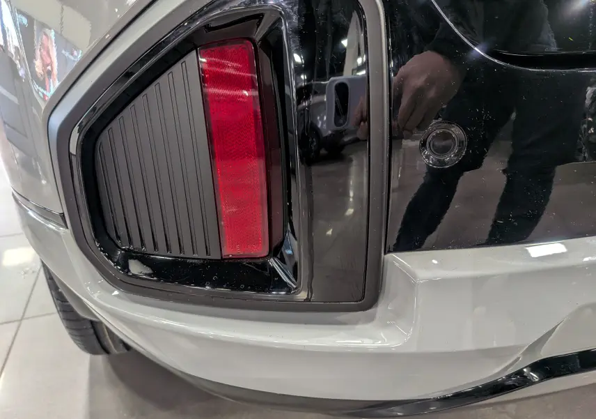 Gros plan sur le feu arrière gauche du KIA SPORTAGE gris céramique avec toit noir, soulignant le design moderne et anguleux.