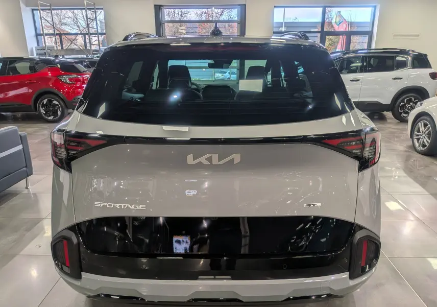 Vue arrière du Kia Sportage 2025 gris céramique avec toit noir et détails noirs brillants sur le hayon et les feux.