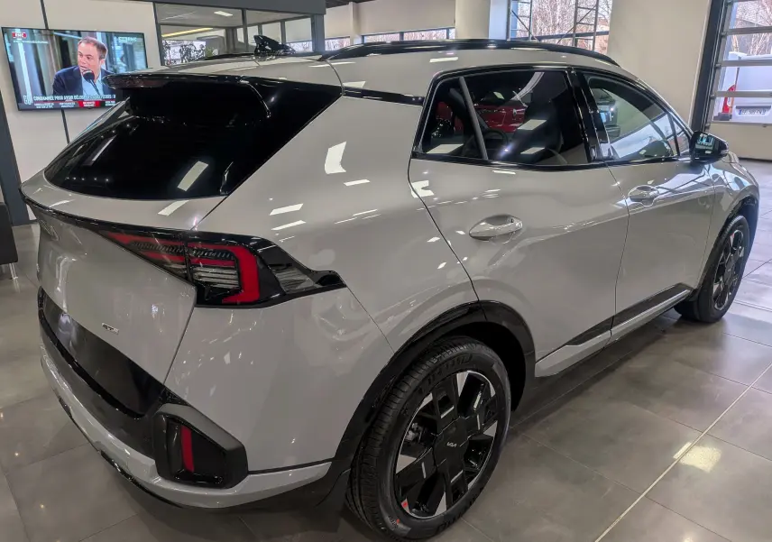Vue 3/4 arrière droite du KIA Sportage 2025 gris céramique avec toit noir et jantes noires distinctives.
