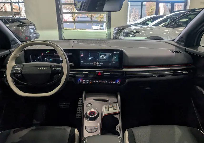 Intérieur du Kia Sportage 2025 GT Line hybride, tableau de bord moderne avec écran tactile et volant bi-ton noir et beige.