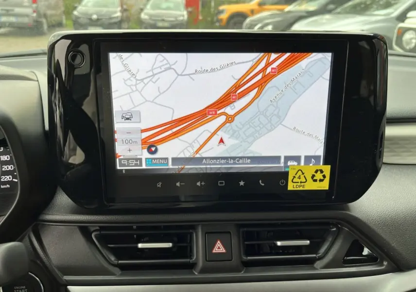 Vue rapprochée de l’écran tactile central du Suzuki Swift 2025 avec navigation GPS affichée et tableau de bord noir.