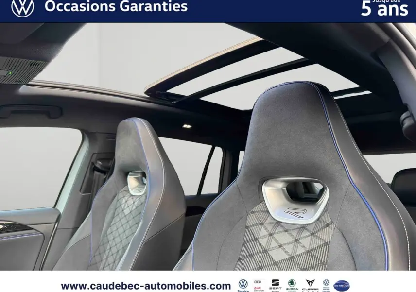 Intérieur du Volkswagen Tiguan eHybrid 2025, vue sur sièges sport R gris avec surpiqûres bleues et toit ouvrant panoramique.