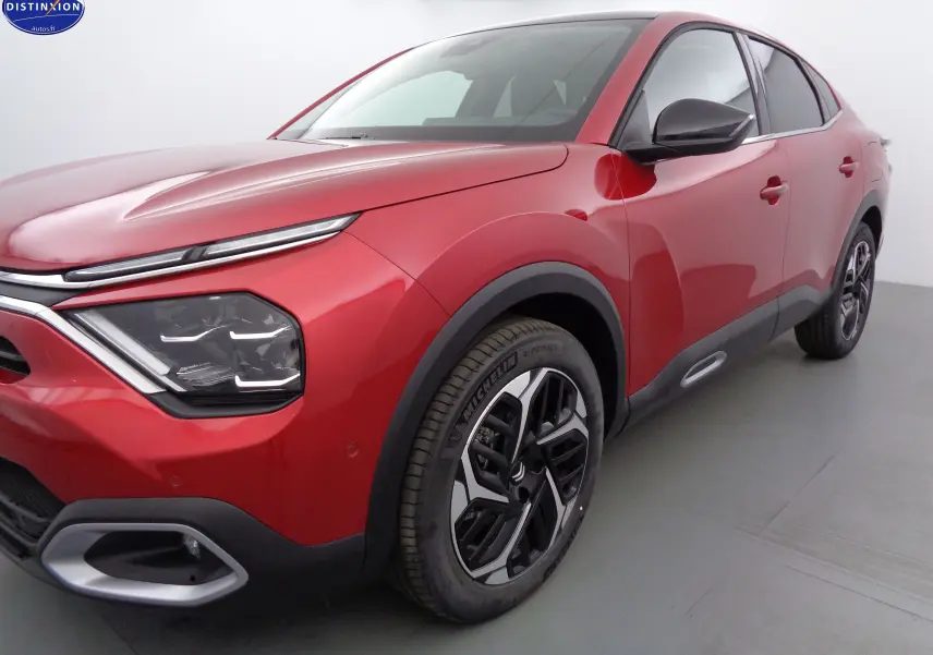 Vue 3/4 avant droit d'une Citroën C4 X rouge Elixir métal avec phares LED et jantes alliage bicolores.