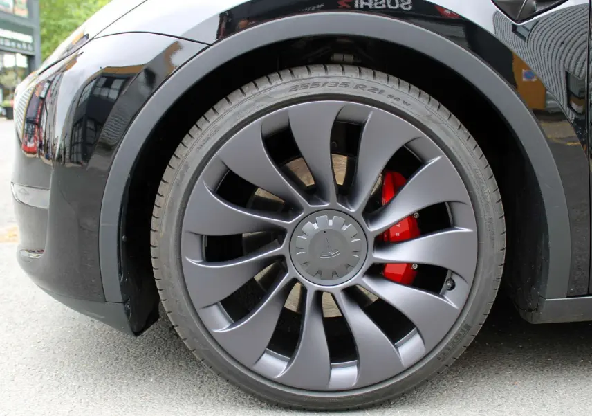 Gros plan sur la roue avant gauche noire métal d'une Tesla Model Y 2024 avec étrier de frein rouge visible.