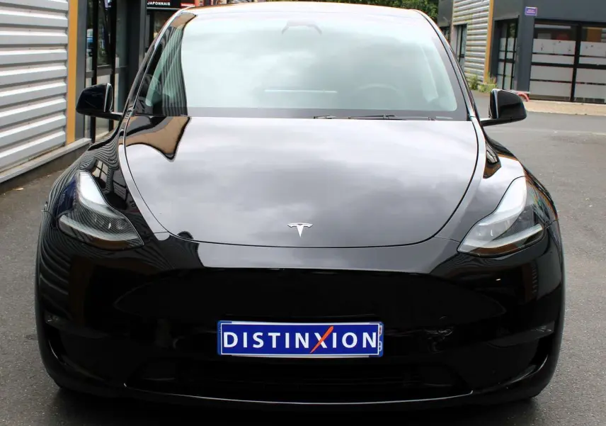 Vue frontale d'une Tesla Model Y noire métal 2024 avec logo distinctif et plaque d'immatriculation Distinxion.