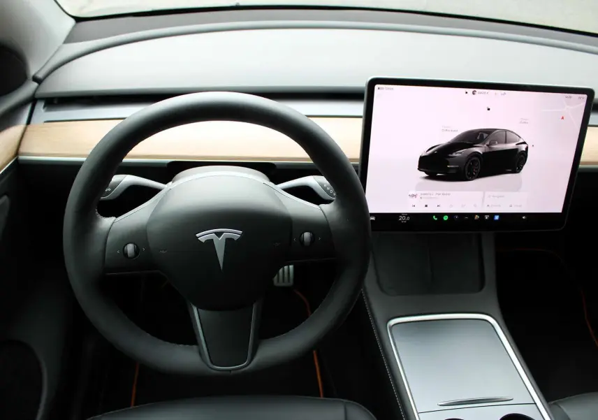 Intérieur Tesla Model Y 2024 noir métal, vue centrée sur le volant et l'écran tactile affichant le véhicule noir.