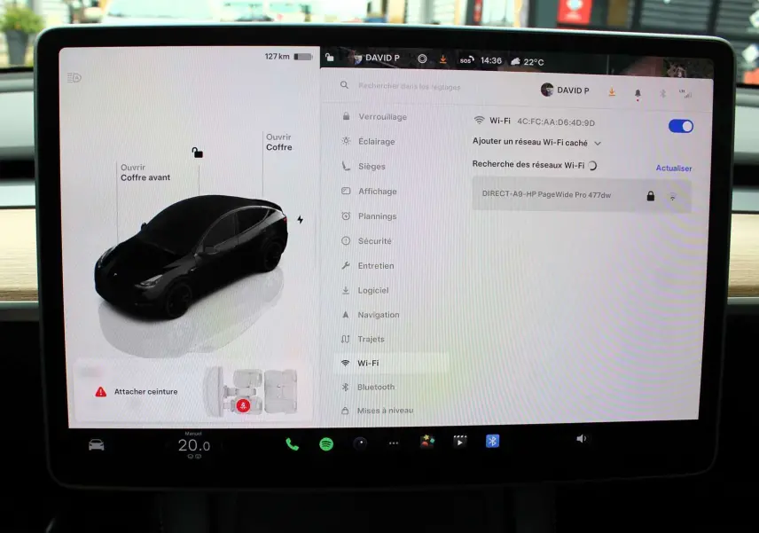 Écran tactile intérieur montrant la Tesla Model Y noir métal en vue 3/4 avant avec options d'ouverture des coffres.