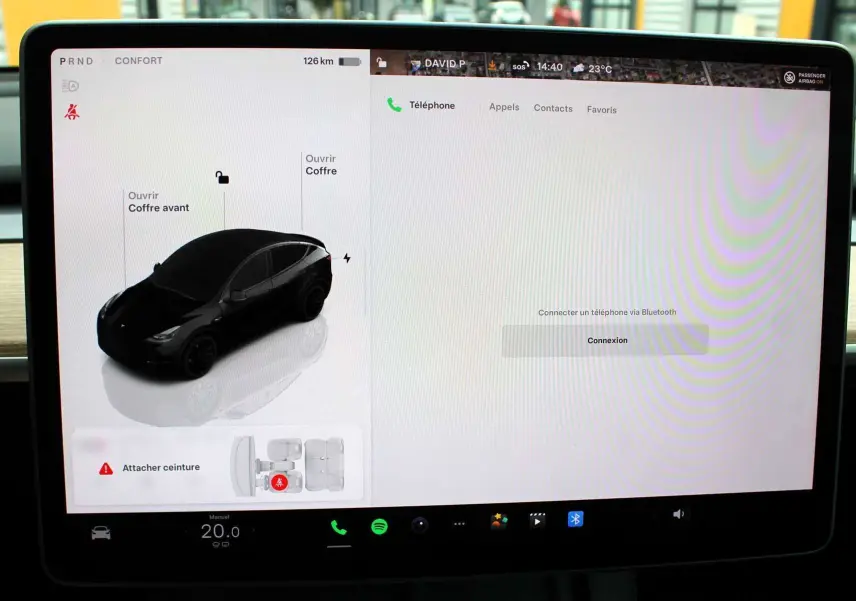 Écran tactile central affichant la Tesla Model Y noire métal en vue 3/4 avant sur l'interface de contrôle du véhicule électrique.