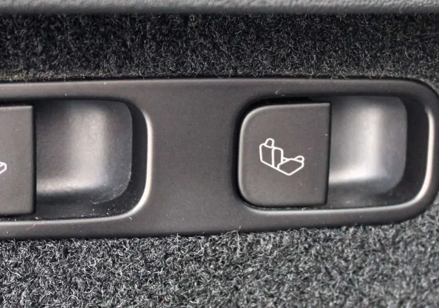 Gros plan sur les boutons de rabattement des sièges arrière du Tesla Model Y noir métal 2024, finition Performance.