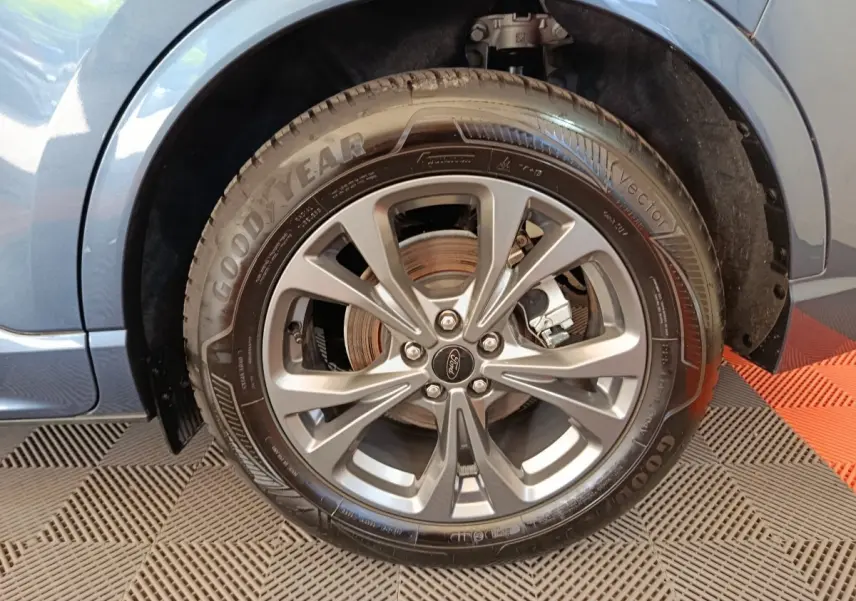 Gros plan sur la roue avant droite du Ford Kuga bleu 2024, mettant en valeur la jante alliage et le pneu Goodyear.