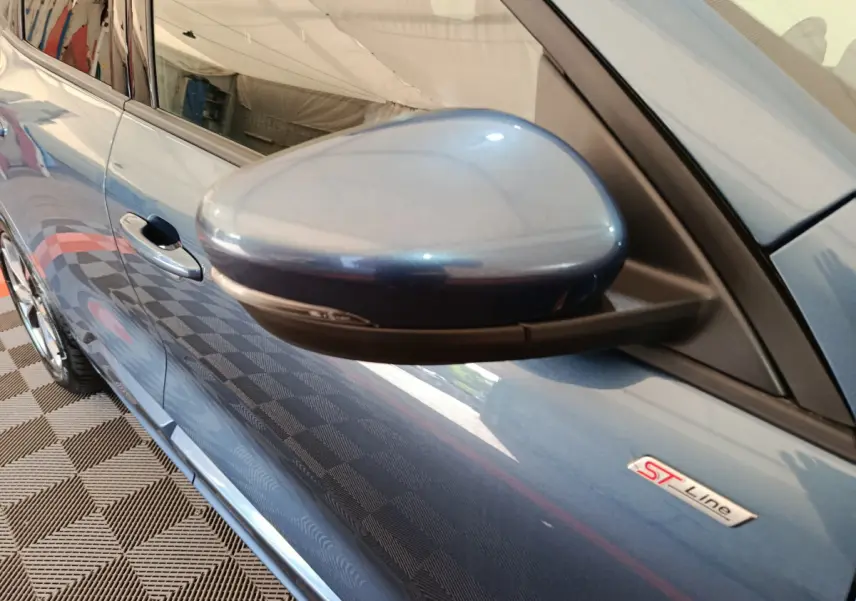 Gros plan sur le rétroviseur côté gauche d'un Ford Kuga bleu 2024 version ST Line avec badge ST Line visible.