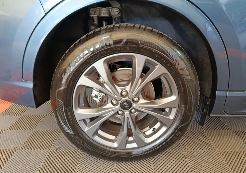Gros plan sur la roue arrière droite du Ford Kuga bleu 2024, avec jante alliage et pneu Goodyear visible.