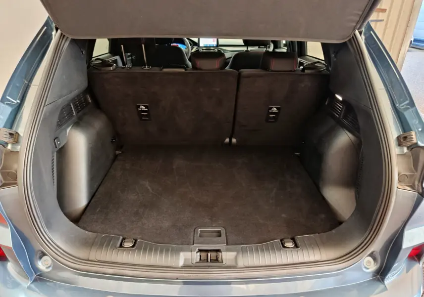 Coffre ouvert d'un Ford Kuga bleu 2024, vue arrière montrant l'espace de chargement et la banquette arrière noire.